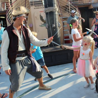 Pirate ship crew member and little girl sword fighting