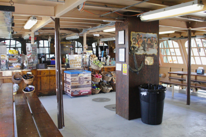 Inside of a themed ship cafe with snack displays, wooden benches, and nautical decor.