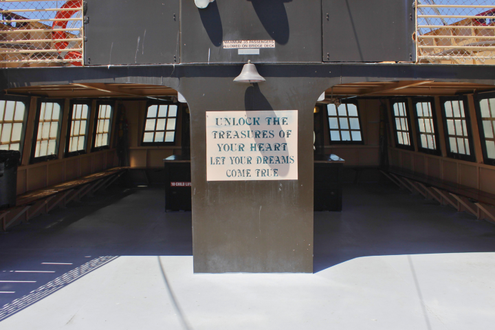 Sign on ship deck reads 'Unlock the treasures of your heart, let your dreams come true.'
