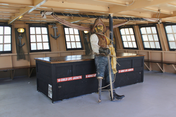 Pirate statue on ship deck with windows, anchors, and life-jacket storage labeled for adults and children.