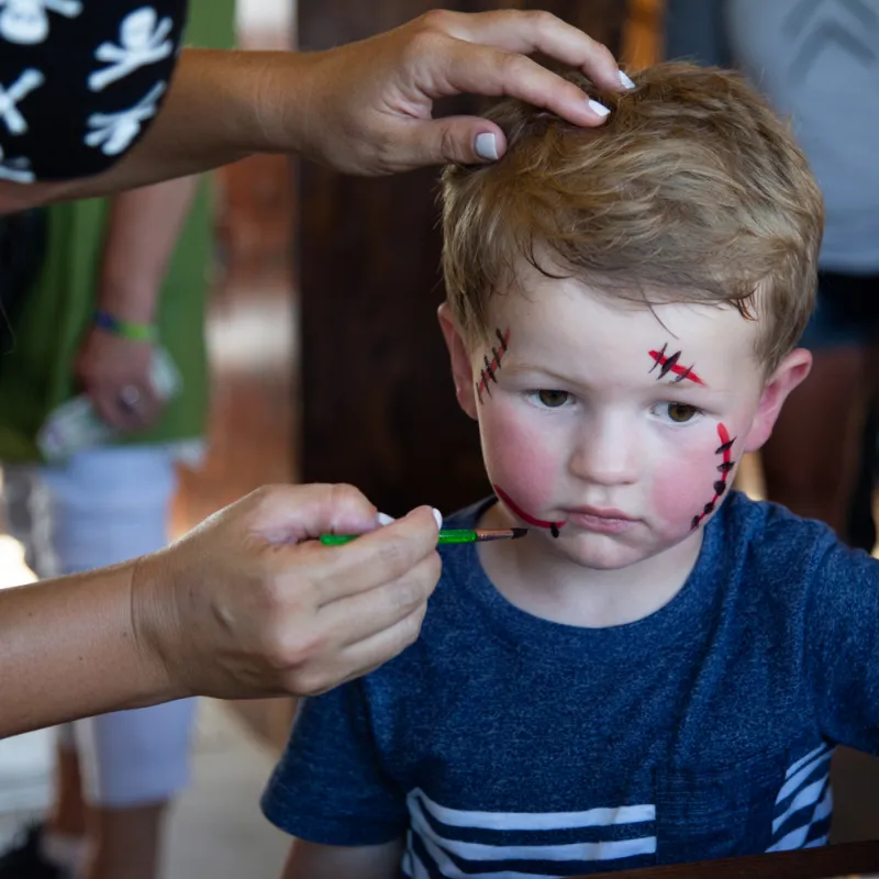 little boy has his face painted on a pirate ship tour