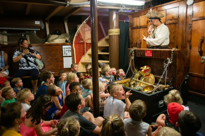 group of people watching pirate ship crew member telling stories