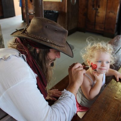 little girl having her face painted by Buccaneer crew member