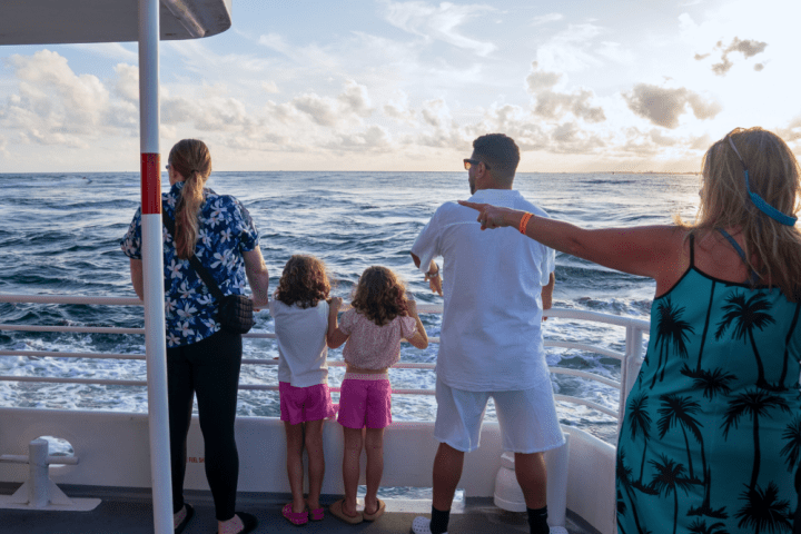 People on a boat deck watching the ocean during a sunny day.