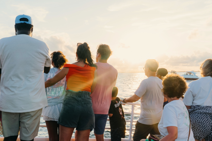 People on a boat watching sunset over the ocean.