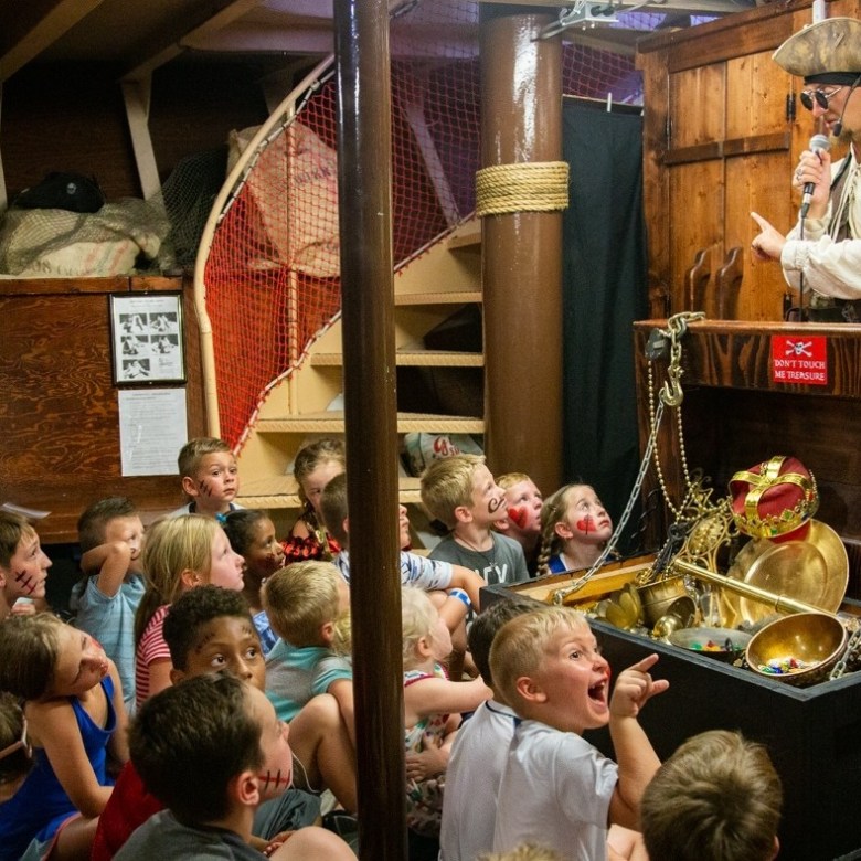 a group of kids hearing a pirate's tale of buried treasure